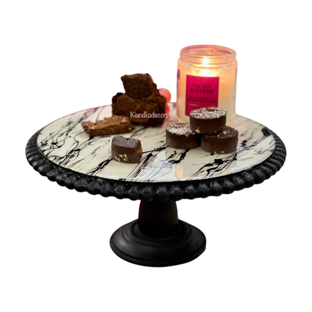 Marble-patterned cake stand with brownies and a candle.